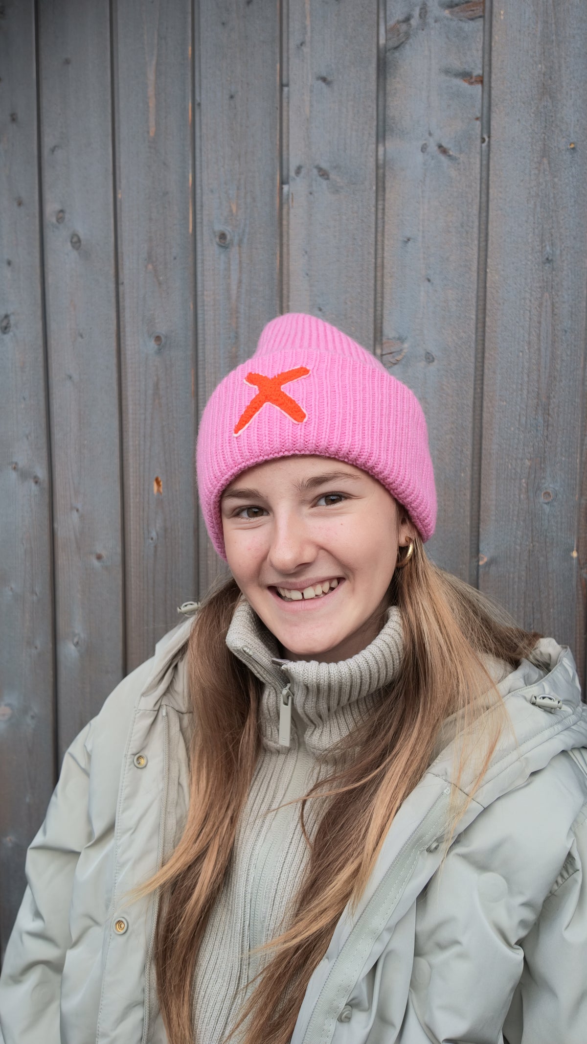 pinke Haube mit orangenem X